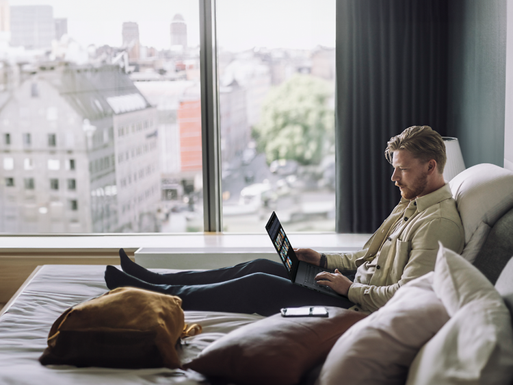 Man on a sofa working with Asus ProArt P16 H7606 laptop on his lap