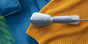 Handhållen steamer - Ljusblå Philips steamer används på gult tyg.