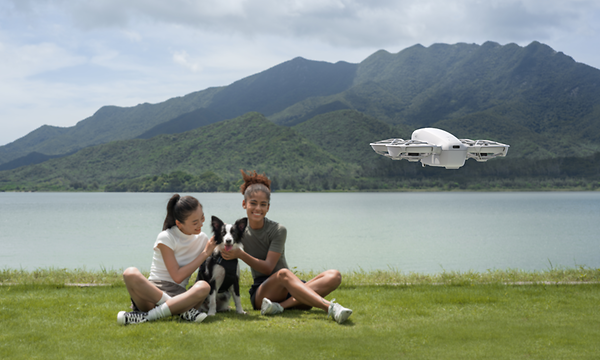 Two girls sitting next to a lake and using DJI Neo Drone 
