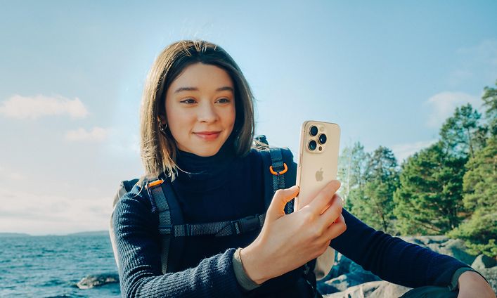 Woman with backpack holding an iPhone 16 Pro