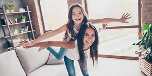 Inomhusklimat med en tjej och en mamma som låtsas flyga tillsammans i vardagsrummet.