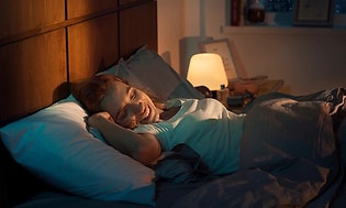 Kvinna använder smart belysning för att vakna upp till varmt ljus.