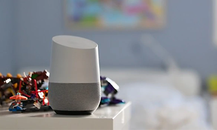 Google Home-enhet placerad på ett bord i ett barnrum med leksaker bredvid. Övriga rummet är oskarpt.