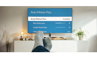 Bilden visar en stor TV med meny-sida "auto motion plus" och i förgrunden två fötter med grå sockar.