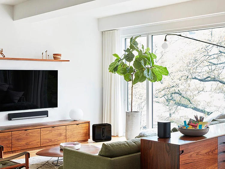 Modernt vardagsrum med platt-TV på väggen, soundbar under och flera smarta högtalare runt om i rummet.