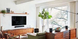 Modernt vardagsrum med platt-TV på väggen, soundbar under och flera smarta högtalare runt om i rummet.