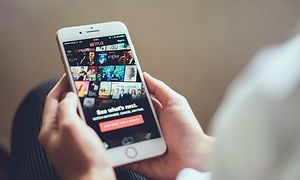Person med mobil i handen, streamar Netflix.