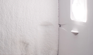 Insidan av ett tomt kylskåp med is eller frost längs med hela innerväggen.