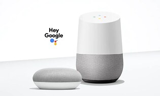 Google home och google mini i grått och vitt med texten "Hey Google". Neutral vit bakgrund.