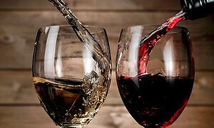 Vin som hälls upp i vinglas, till vänster ett glas med vitt vin och till höger ett glas med rött. 
