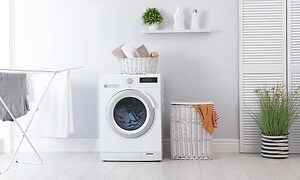 Välorganiserad tvättstuga med torkställ en tvättkorg och några växter. I mitten står en kombinerad tvättmaskin med torktumlare.