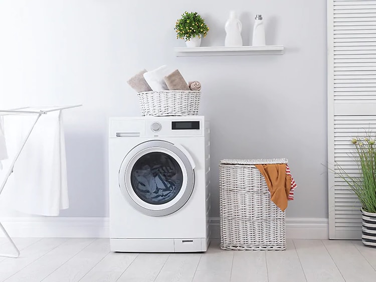 Välorganiserad tvättstuga med torkställ en tvättkorg och några växter. I mitten står en kombinerad tvättmaskin med torktumlare.