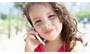 En ung flicka gör ett nöjt ansikte medan hon pratar i sin mobiltelefon.