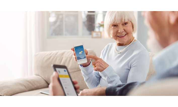Ett äldre par visar varandra något på sina smartphones.
