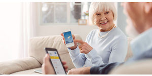 Ett äldre par visar varandra något på sina smartphones.