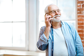 En äldre man talar i sin smartphone och ler.