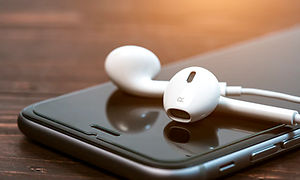 Närbild av In-Ear hörlurar som ligger på mobiltelefon.