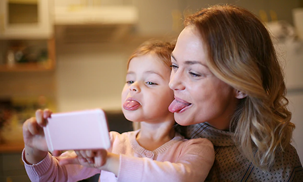 Mor och dotter tar selfie av fula miner i mobiltelefonen.
