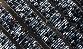 Bild tagen ovanifrån på en stor bilparkering utomhus med flera hundra bilar. 