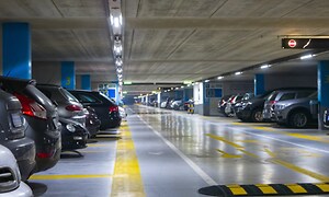 En massa bilar som står parkerade i ett stort bilgarage. 