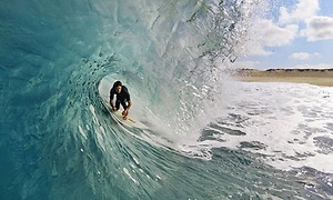 Bild på en man som surfar en stor våg, befinner sig mitt i "tunnelvågen". 
