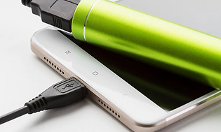 En vit telefon som är ansluten till en grön powerbank som är placerad ovanpå telefonen.