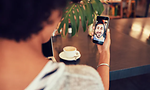 Kvinna i videosamtal med en man på cafe, troligen Facetime. En kopp kaffe på ett bord syns i bakgrunden.