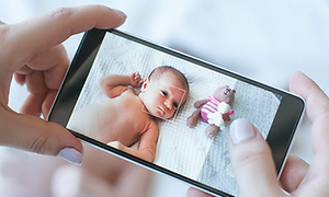 Person på väg att ta en bild av en baby med ett gosedjur med hjälp av en mobilkamera.