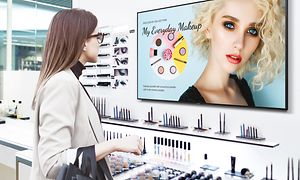 En kvinna i en makeupbutik ser på en Samsung Business TV.