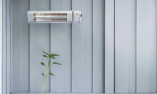 Wall-mounted terrace heater over a green plant and a couch