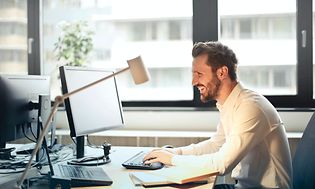 Man sitter och jobbar i ett öppet kontorslandskap med ett headset med mikrofon.