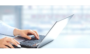 Närbild på en bland bärar dator i grå färg, händer placerade på tangentbordet. 
