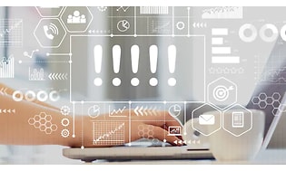 Närbild på händer som skriver på ett tangentbord på en bärbar dator. Brevid står en kopp och i förgrunden syns massa symboler.
