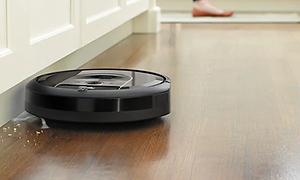 iRobot Roomba i7+ svart robotdammsugare städar upp brödsmulor längs en vägg.