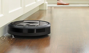 iRobot Roomba i7+ svart robotdammsugare städar upp brödsmulor längs en vägg. 